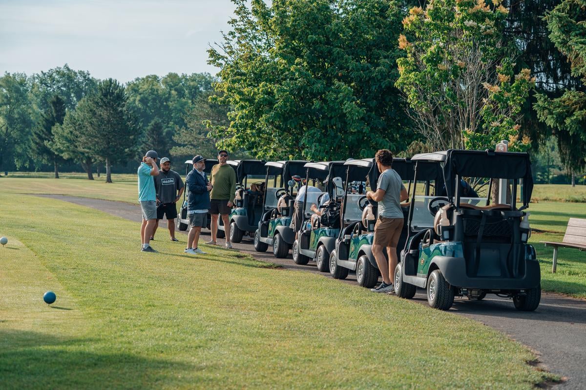 Golfers preparing for a game on a sunny day Group of golfers standing near their carts