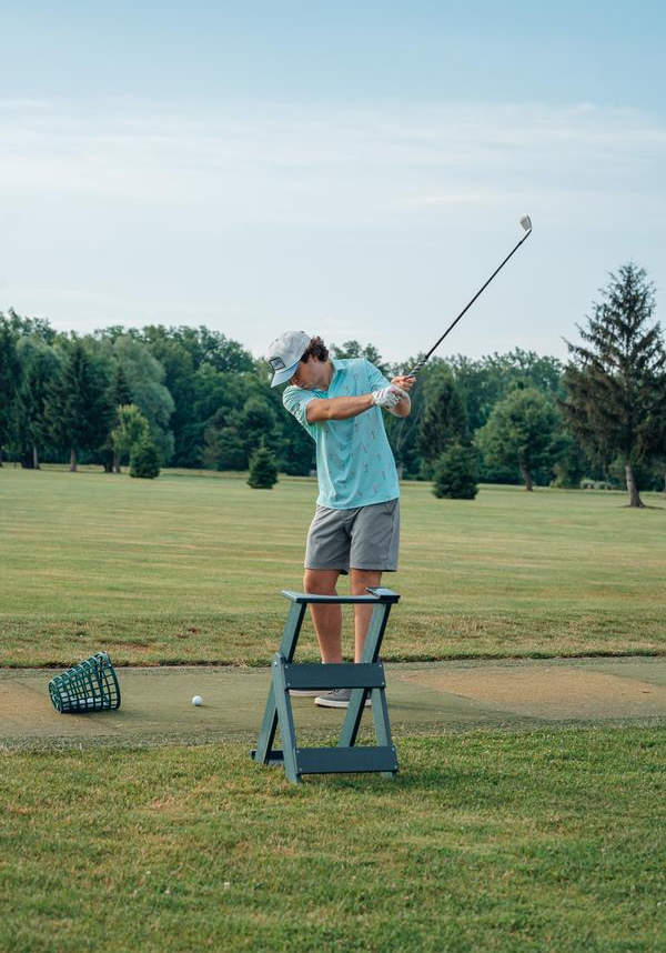 Man in golf attire swinging club on grassy course