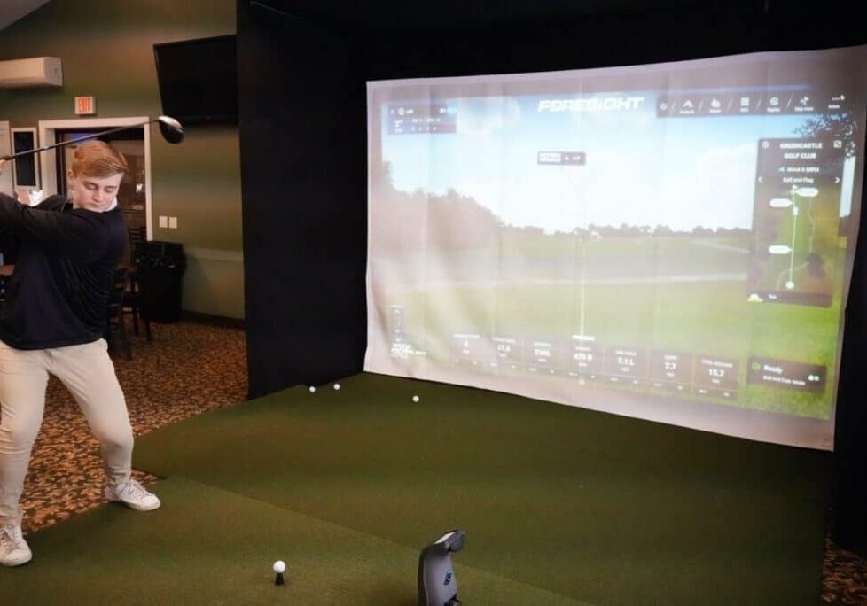 Golf Simulator Indoor Screen Display Man playing golf on indoor simulator. Virtual golf game.