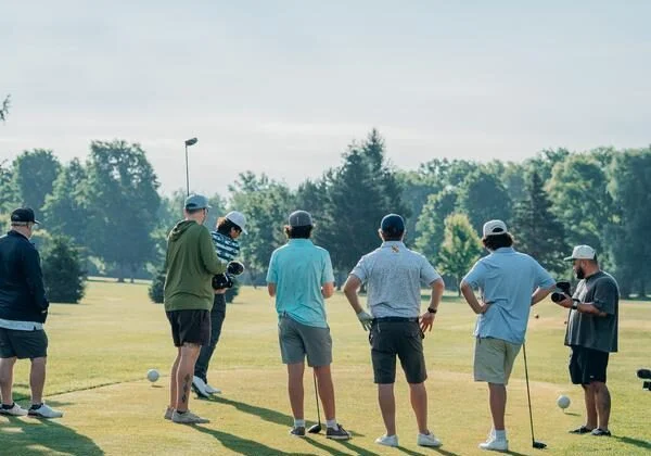golfers standing on a driving range group of golfers on a driving range